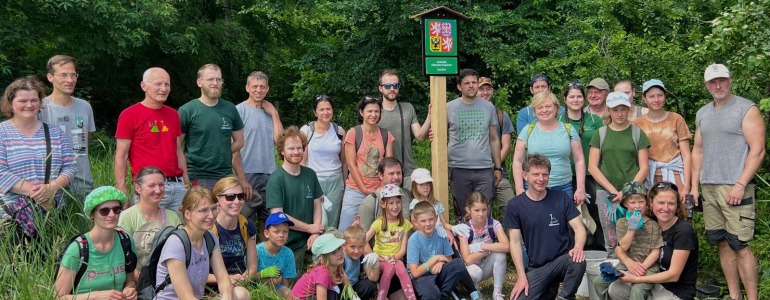 Společná fotografie dobrovolníků u hraniční cedule národní přírodní památky Soutok.